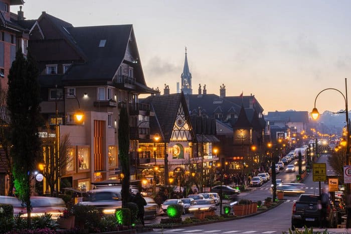 Ruas iluminadas de uma Viagem para Gramado durante o Natal Luz, com árvores decoradas e arquitetura alpina.